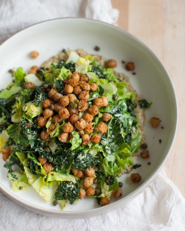 A large white bowl of crispy roasted chickpeas on a caesar salad. 