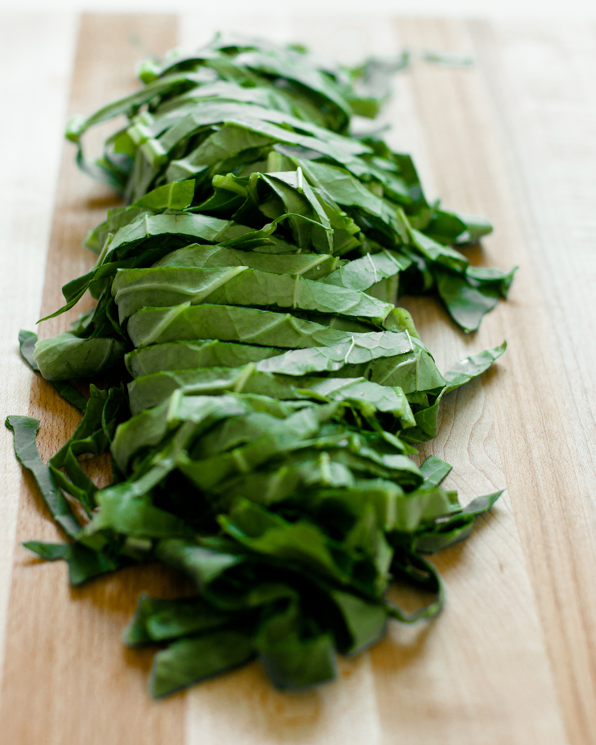 Chopped collard greens on a wooden cutting board.