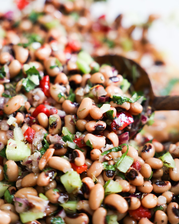 close up of black eyed pea salad in a bowl with spoon