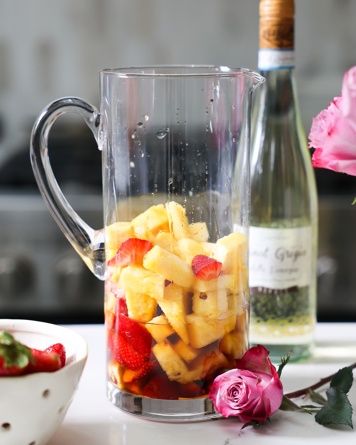 Pineapples and strawberries in glass pitcher.