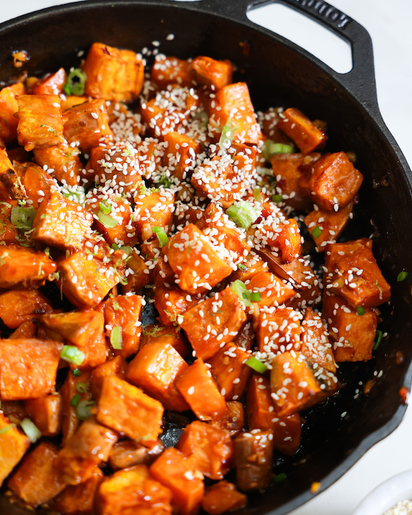 Bright orange glazed sweet potatoes in a black cast iron skillet