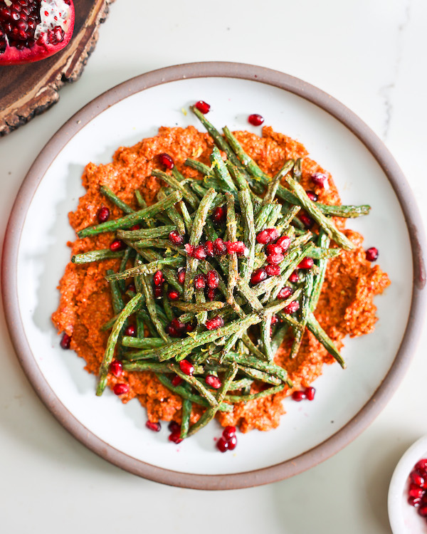 overhead of plated air fryer green beans over muhammara sauce