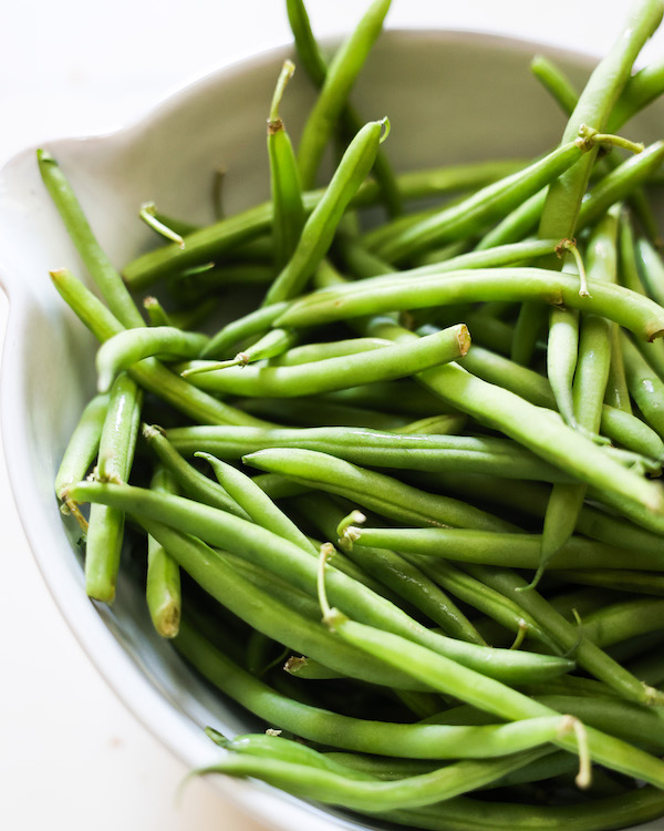 fresh raw green beans in a white bowl