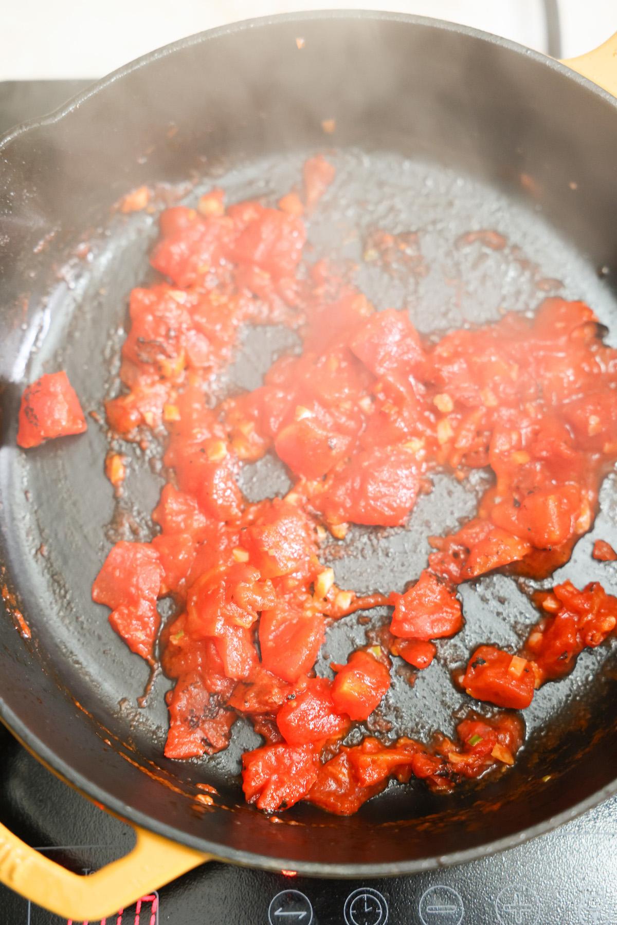 Tomatoes sauteing in a skillet.