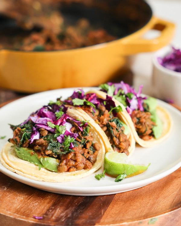 lentil tacos on plate in front of skillet of cooked lentils