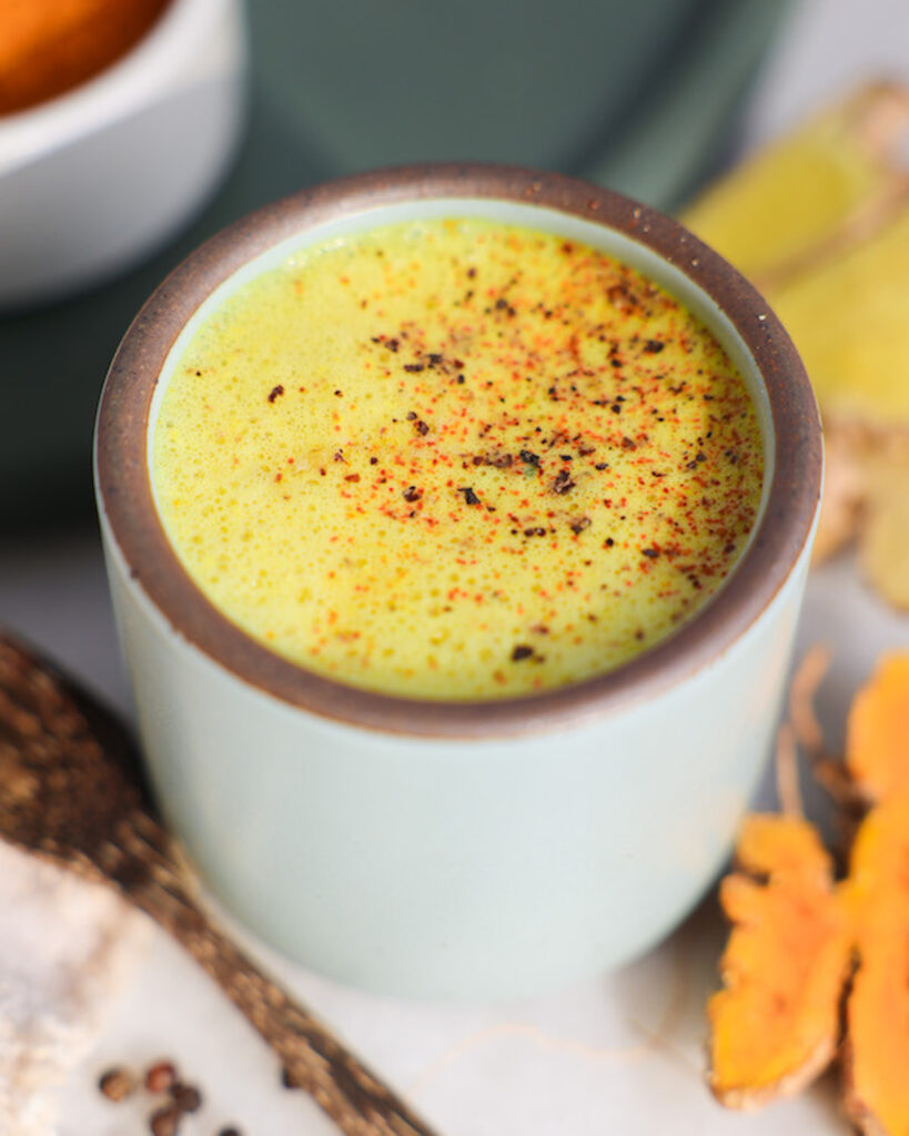 golden milk in a mug surrounded by ingredients