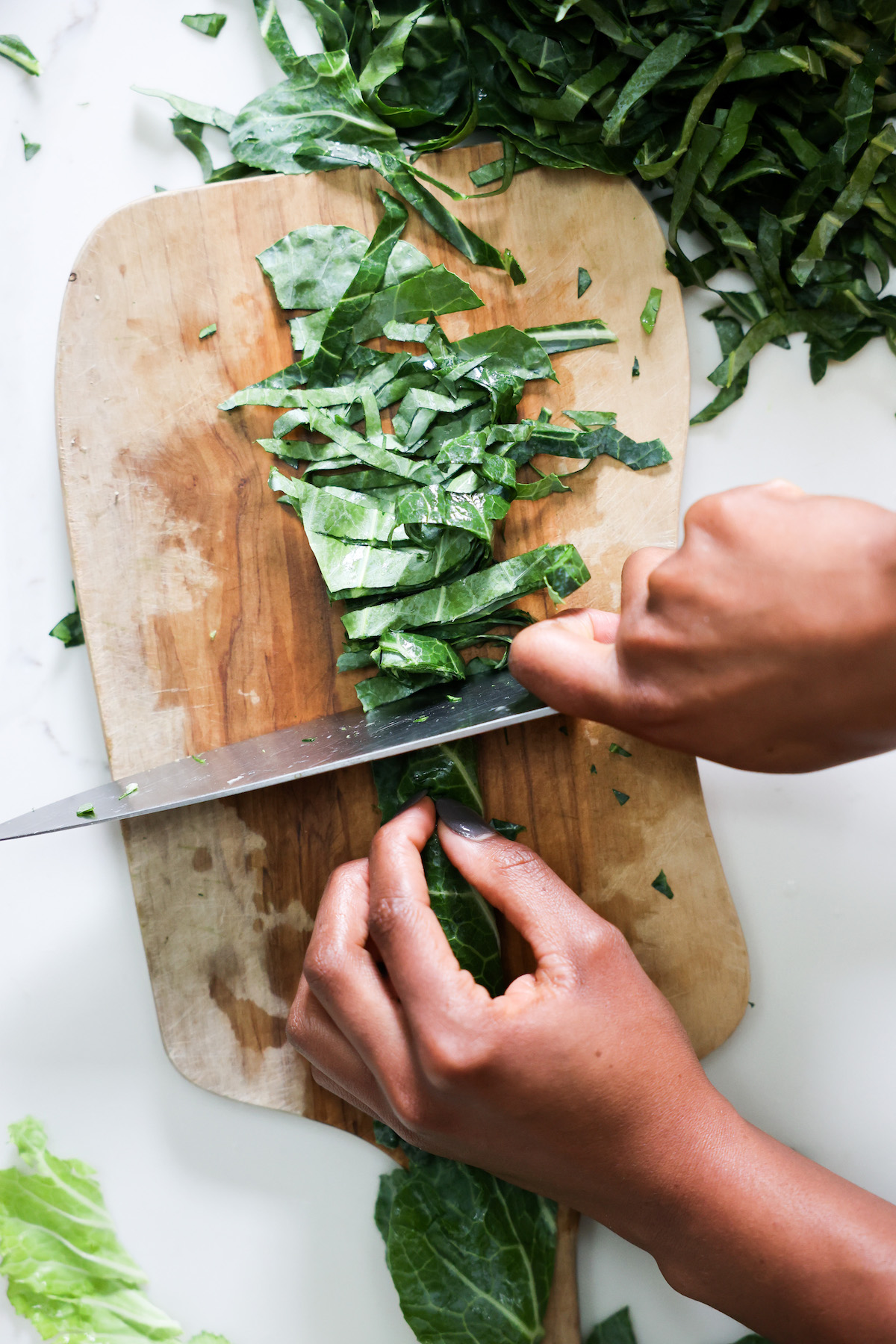 overhead shot of thinly slicing collard greens in chiffonade style