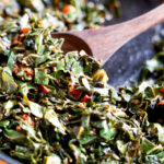 wooden spoon scooping collard greens in a skillet