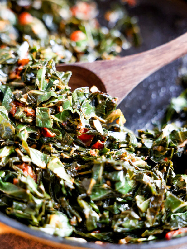wooden spoon scooping collard greens in a skillet