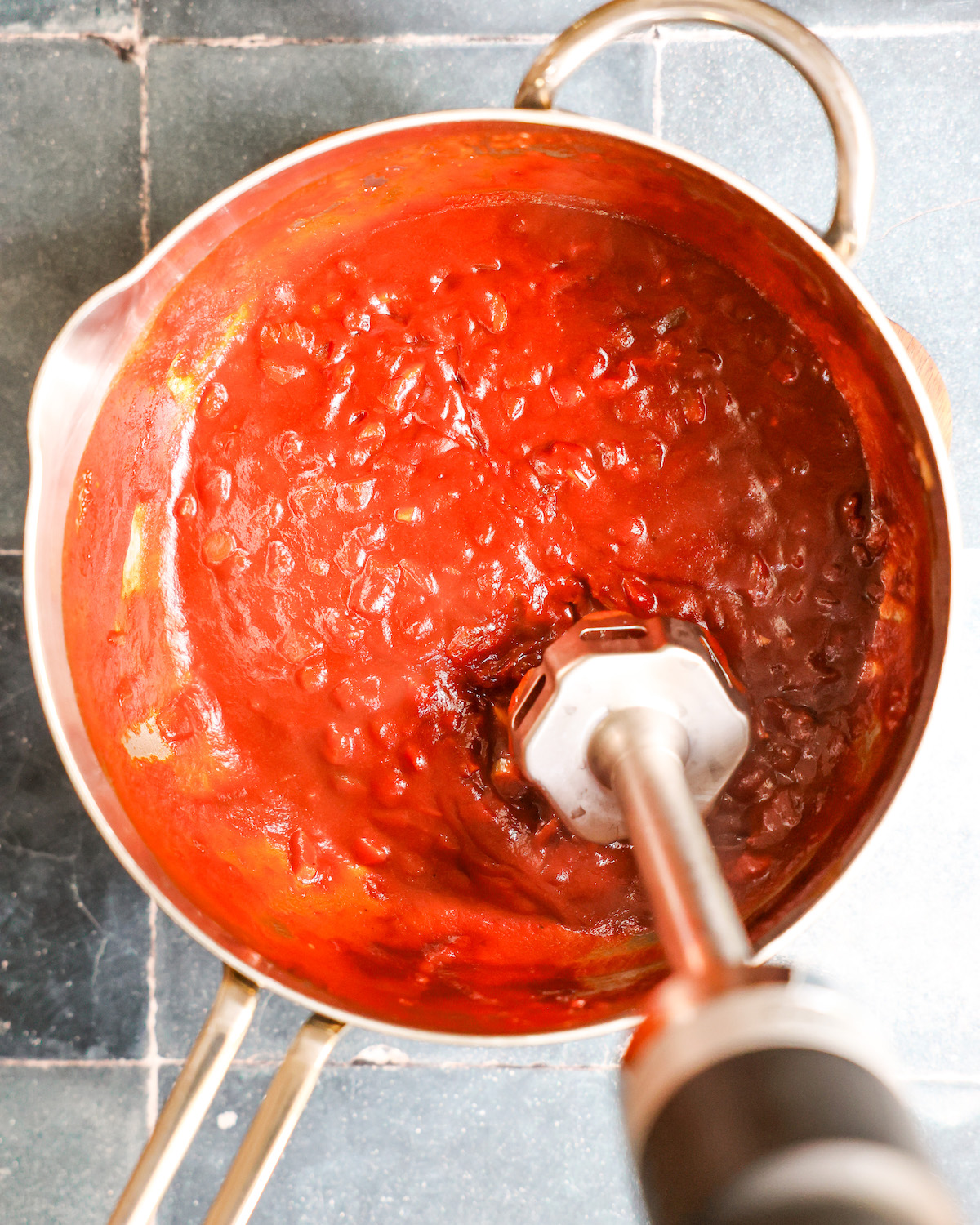 Immersion blender in a pan blending bbq sauce
