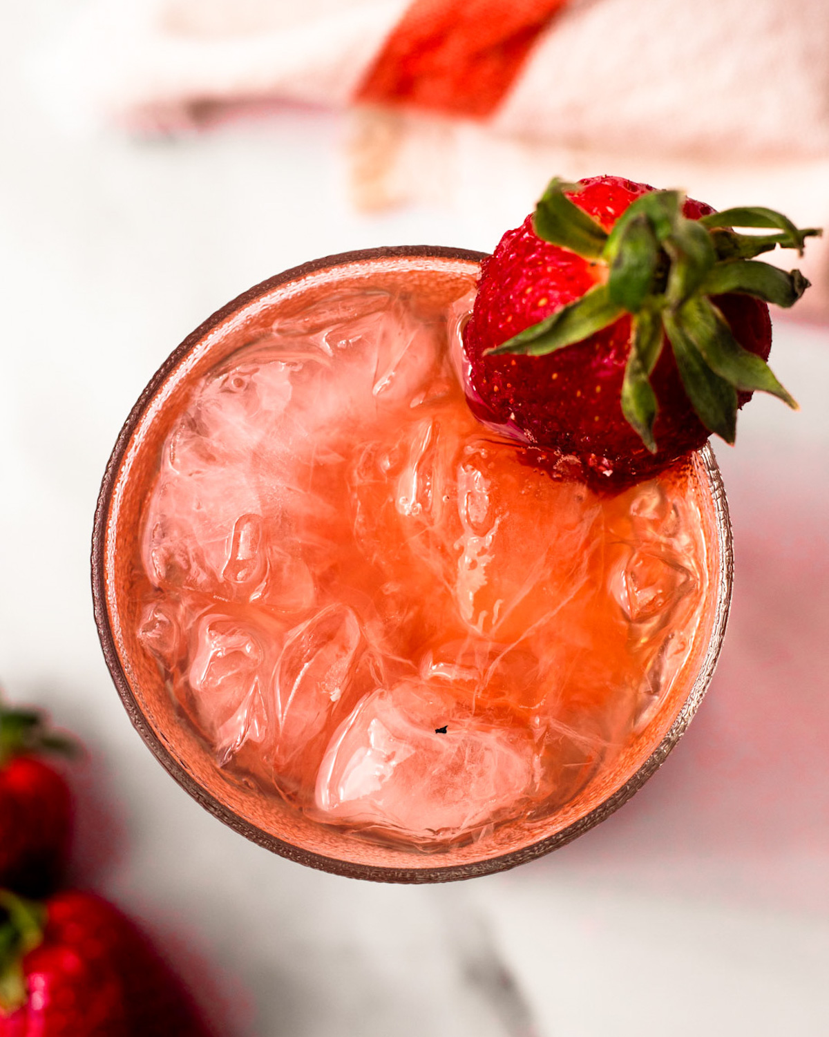 An overhead shot of a glass of strawberry bramble with a strawberry on the side of the glass.