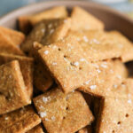 An up-close shot of "cheesy" pumpkin seed crackers in a bowl.
