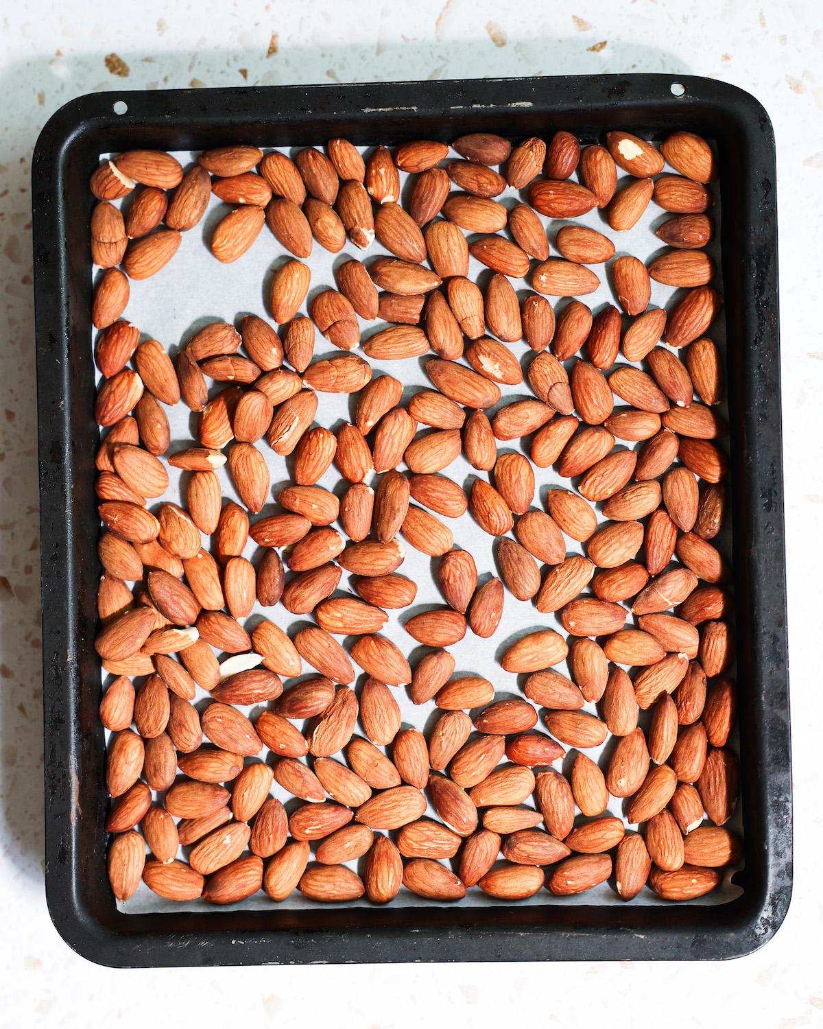 An overhead shot of a pan of tamari almonds before roasting.
