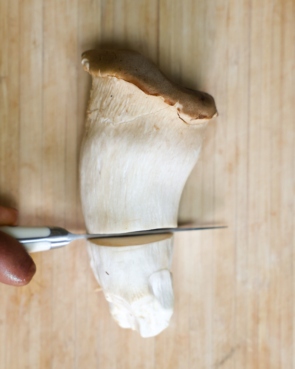 paring knife slicing through a large king oyster mushroom
