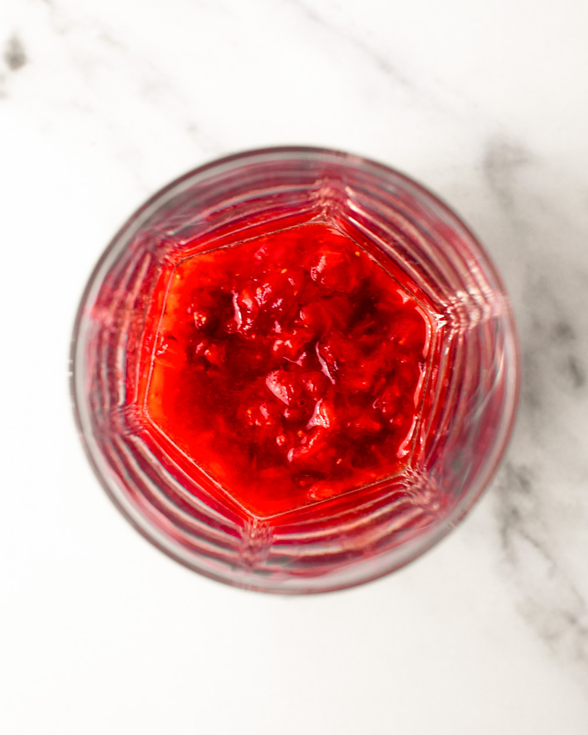 An overhead shot of strawberries muddled in a glass.