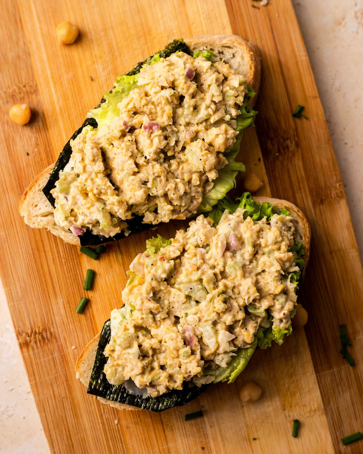 An overhead shot of two slices of vegan chickpea tuna salad on a wooden cutting board.