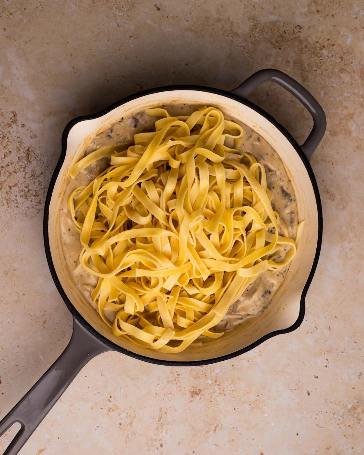 adding pasta to vegan mushroom alfredo sauce