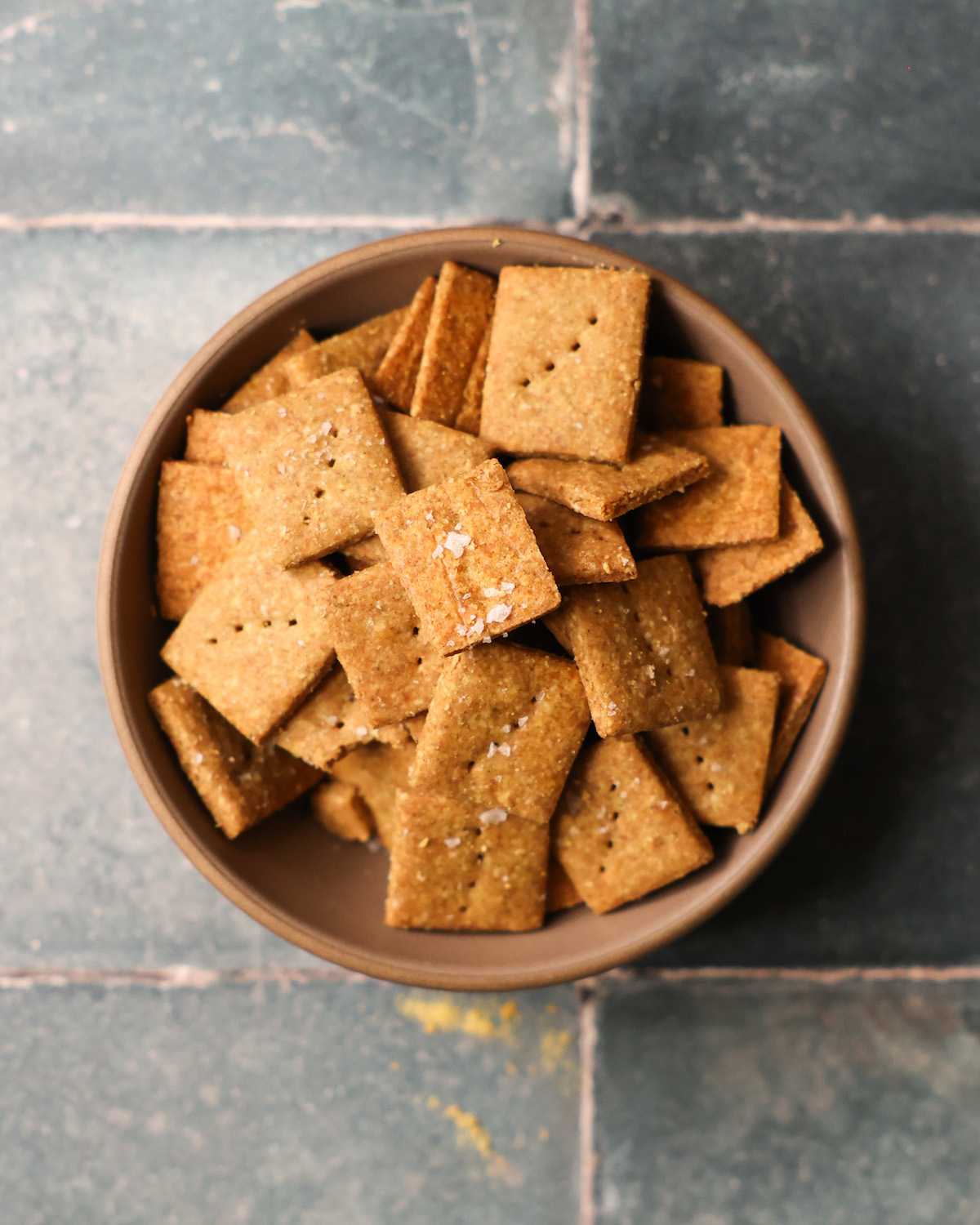 An overhead shot of a bowl of pumpkin seed crackers in a bowl on the counter.