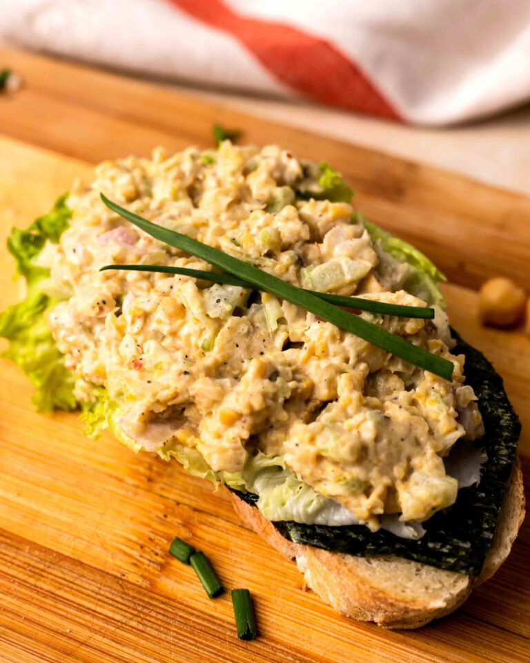 Vvegan chickpea salad on toast on a wooden cutting board.