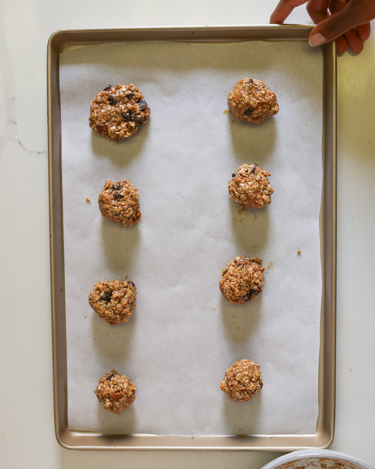 An overhead shot of a baking sheet with tahini chocolate chip cookies on top. A few of the cookies are flattened and others are not.