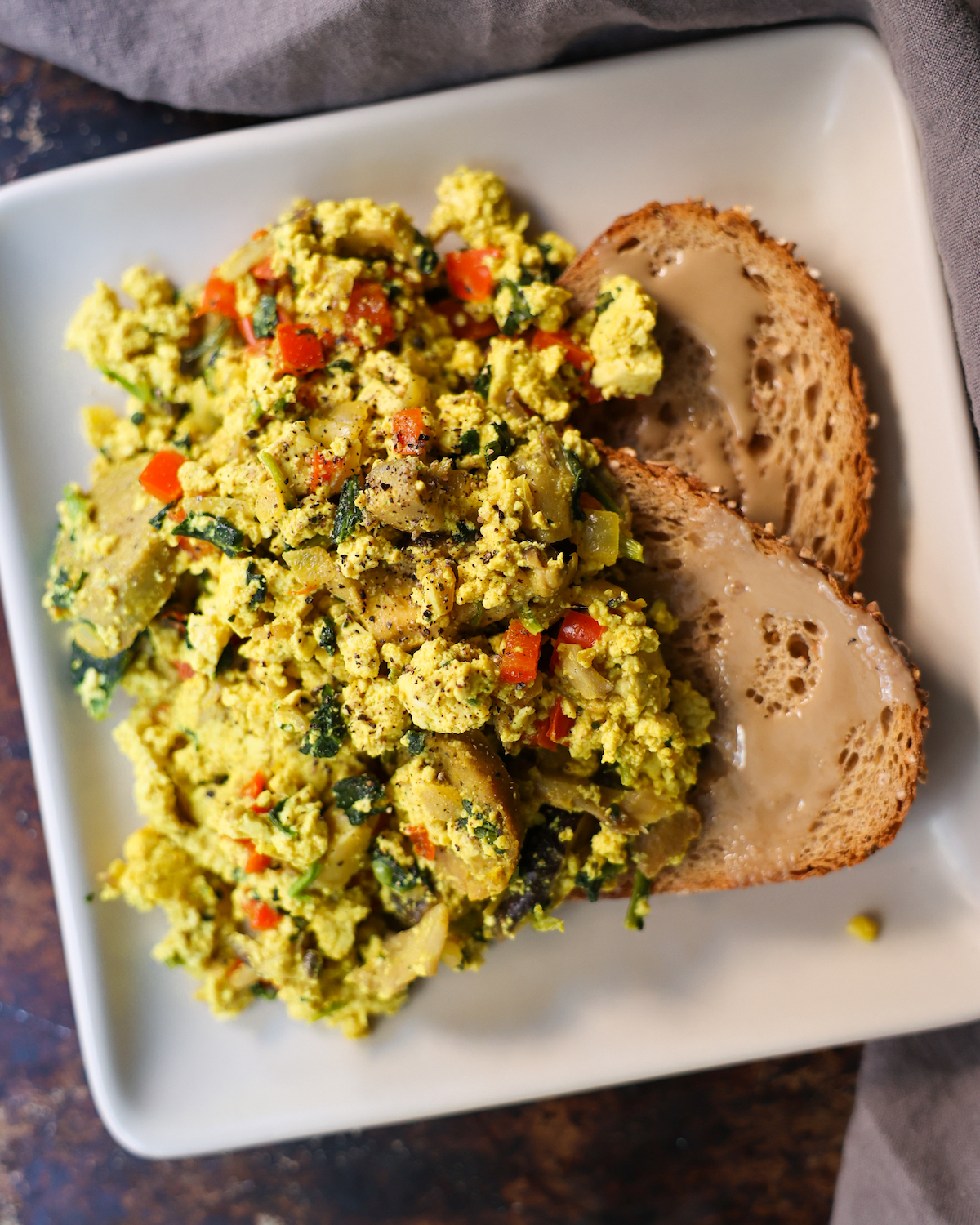 overhead of tofu scramble on a white plate with toast