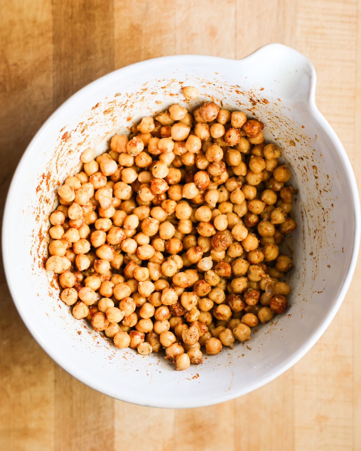 An overhead shot of a bowl of seasoned chickpeas before roasting.