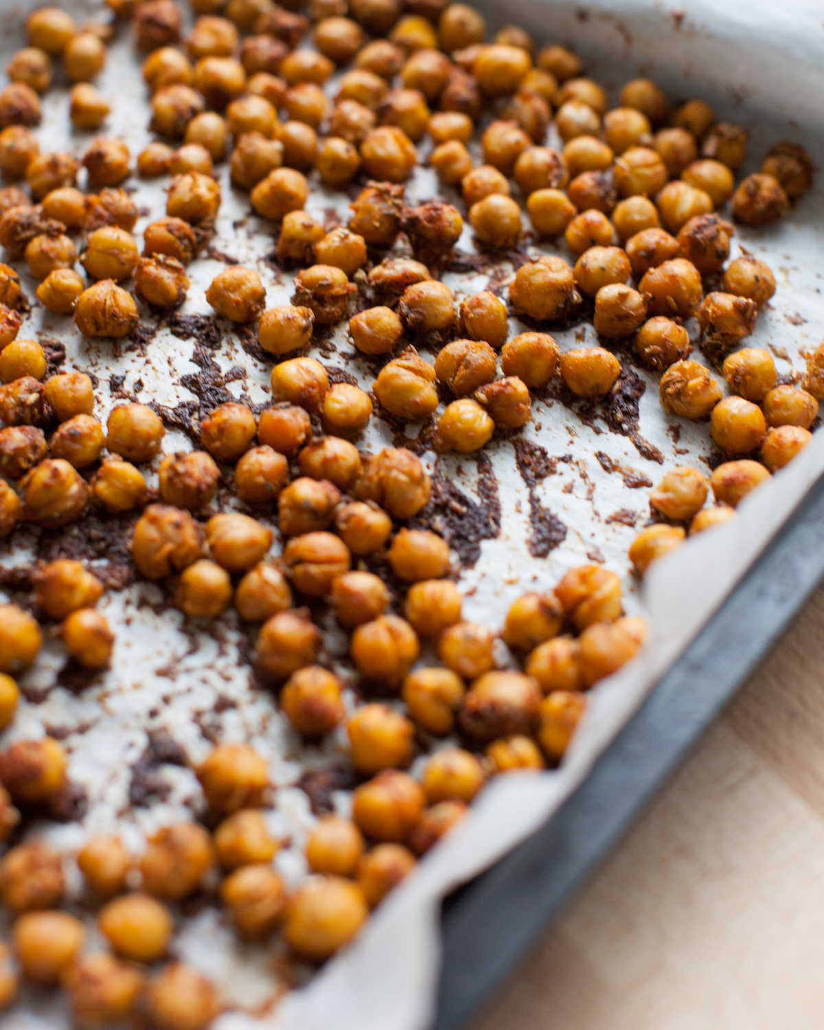 A side shot of a baking tray of roasted chickpeas.