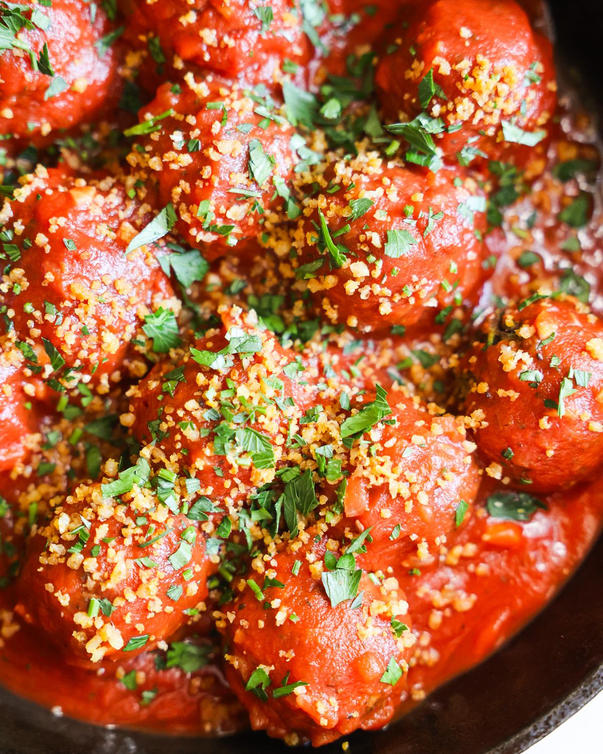 closeup of lentil vegan meatballs covered in tomato sauce