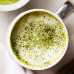 A close-up overhead shot of a oat milk matcha latte sprinkled with matcha.