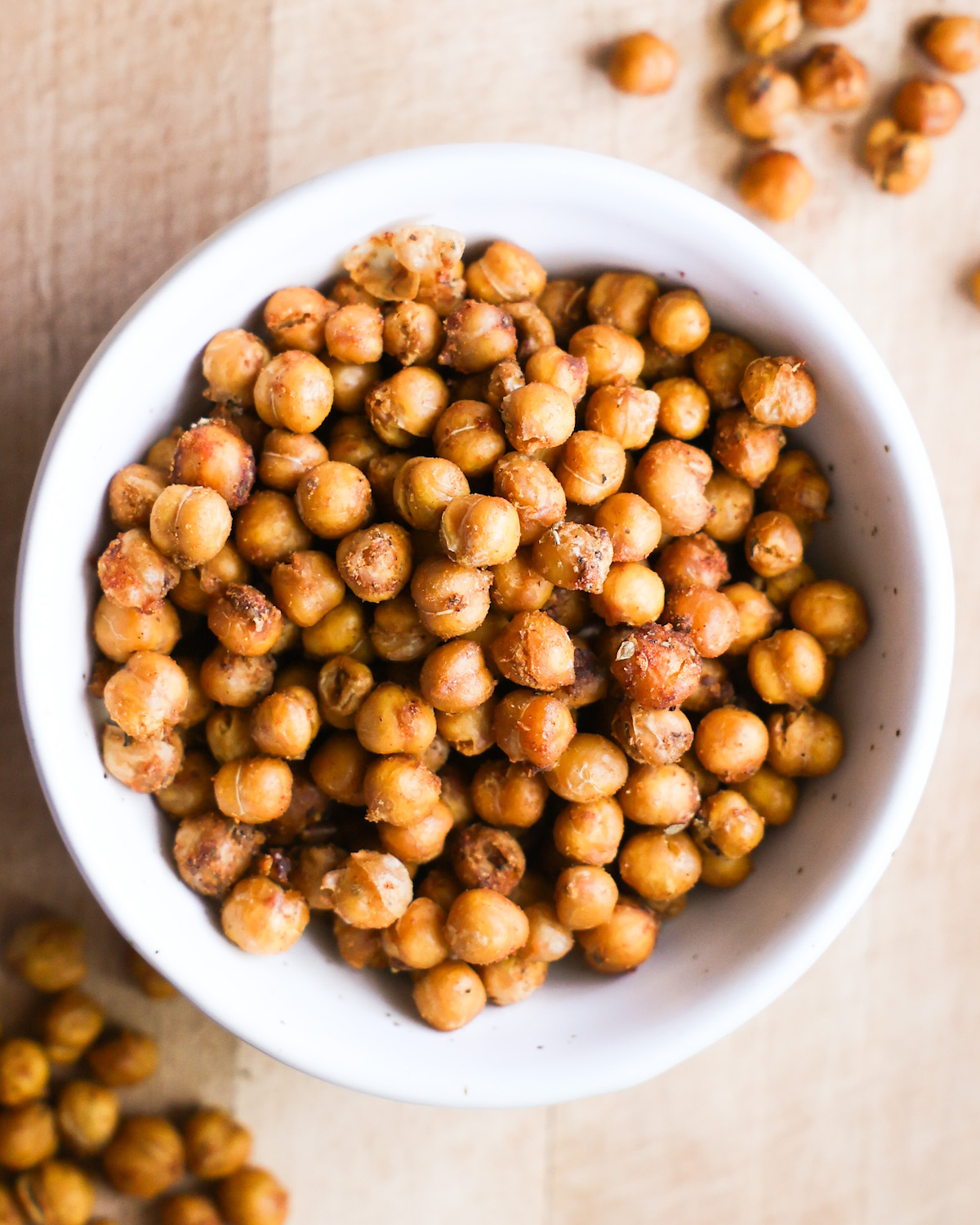 An up-close overhead shot of a white bowl of roasted chickpeas.