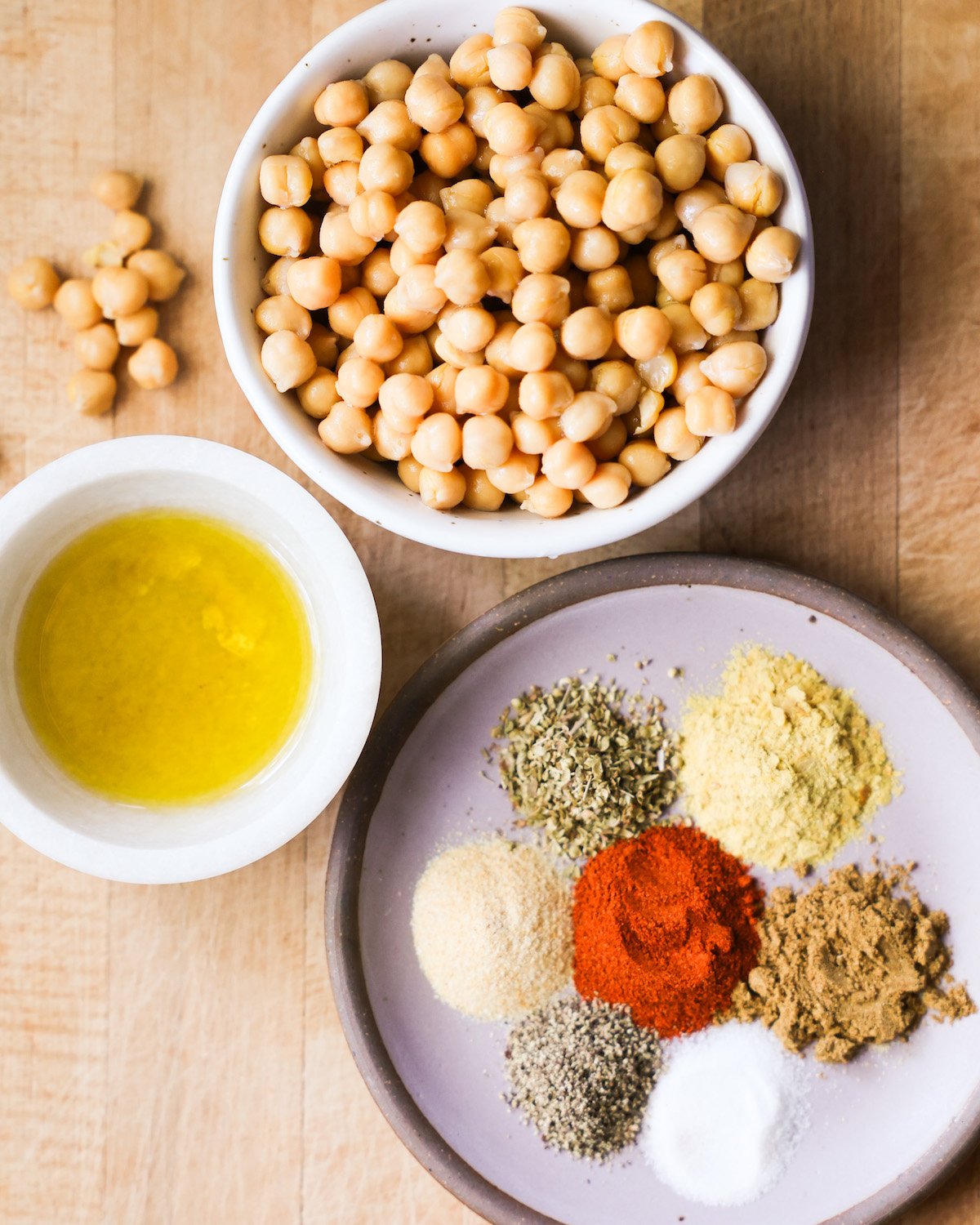 All of the ingredients for roasted chickpeas: canned chickpeas, olive oil, nutritional yeast, and spices.
