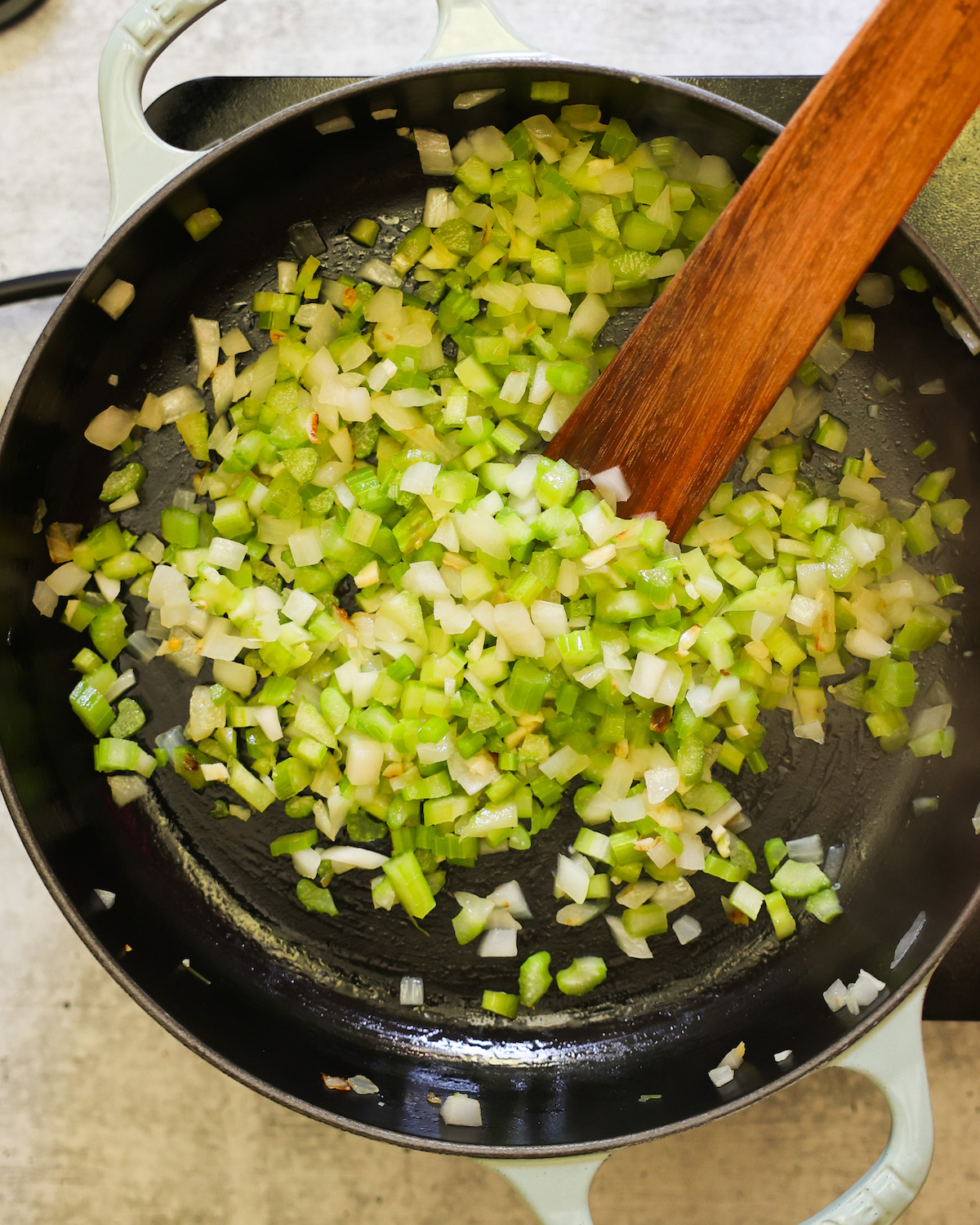 onions and celery sautéing in a black skillet