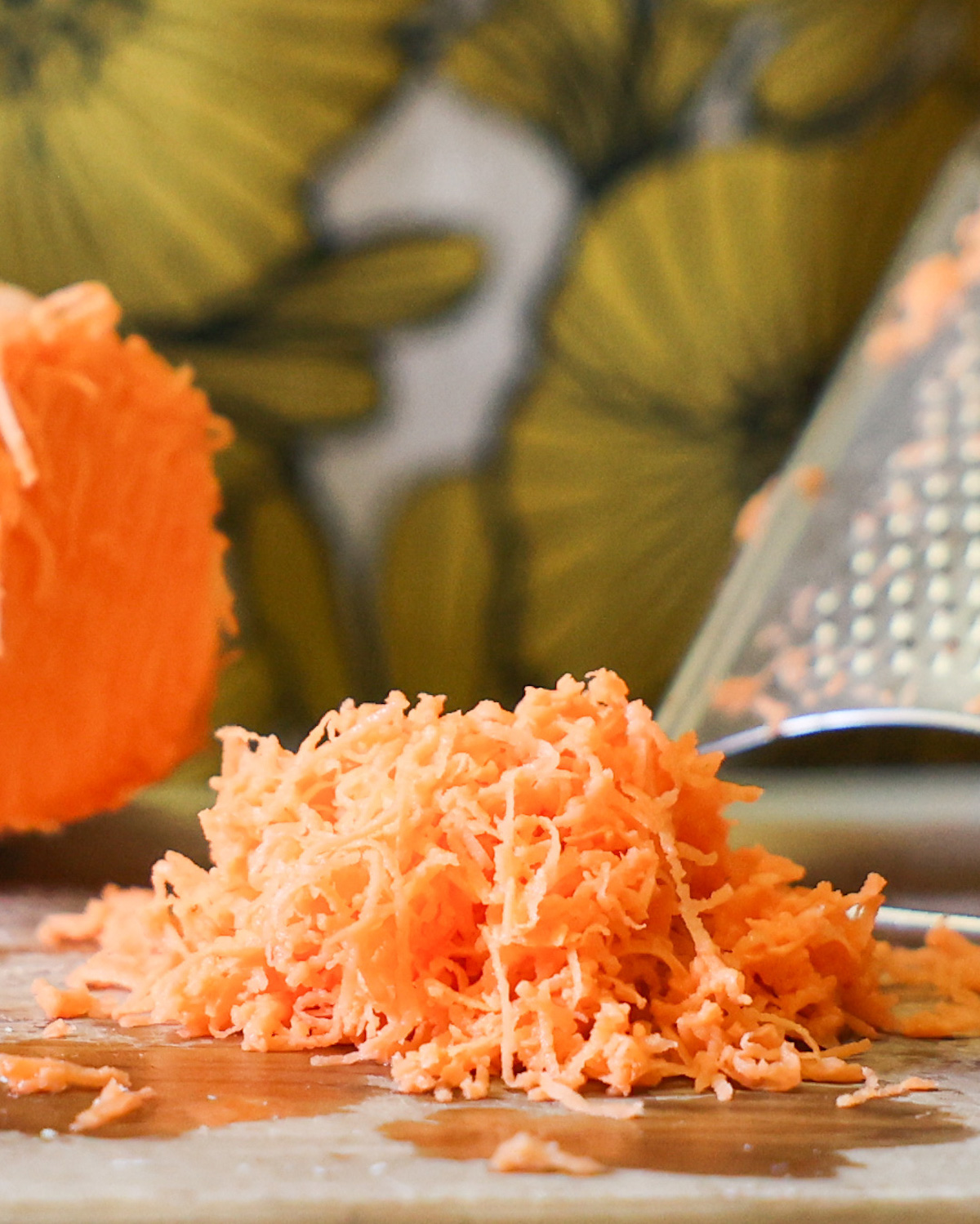 An up-close side shot of shredded sweet potato on a cutting board.