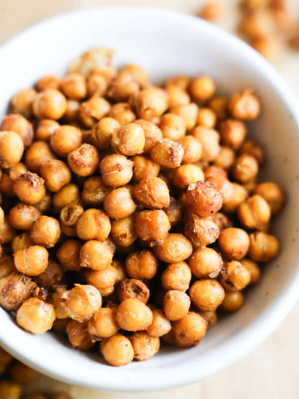 A close up shot of a white bowl of roasted chickpeas.
