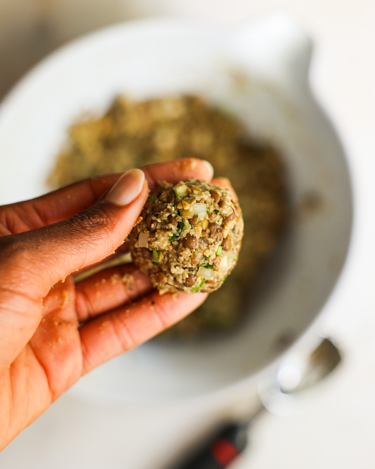 overhead of hand holding an uncooked vegan meatball