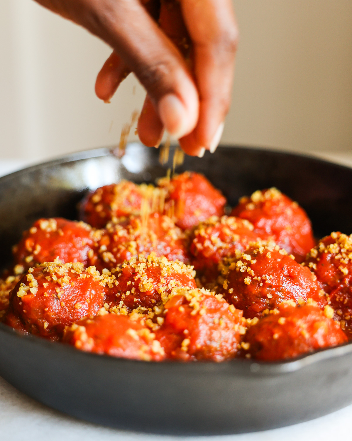 sprinkling vegan parmesan over lentil meatballs