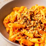 An up-close angled shot of a bowl of arrabbiata sauce on penne.
