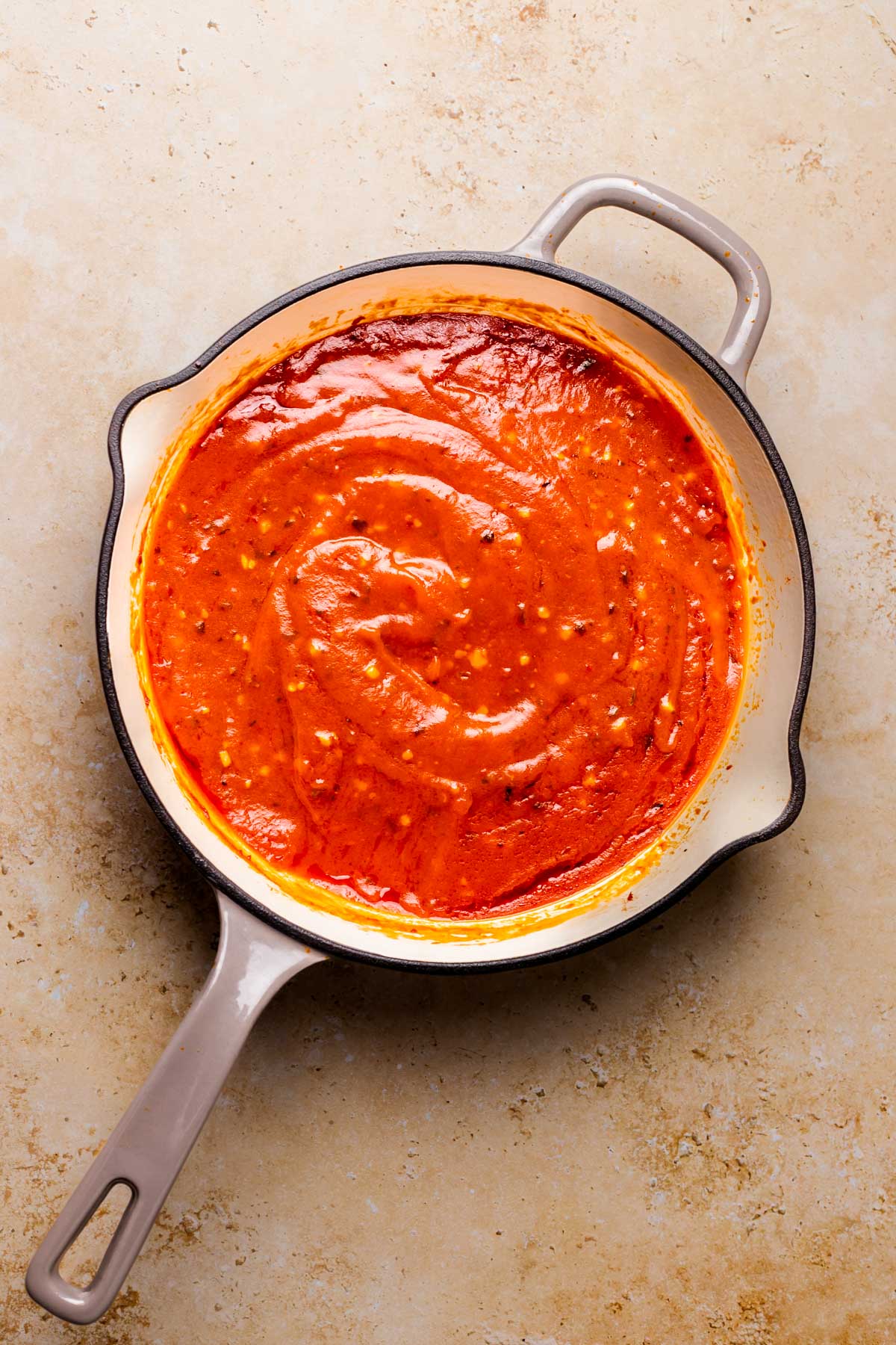 An overhead shot of a large skillet of simmered arrabbiata sauce.