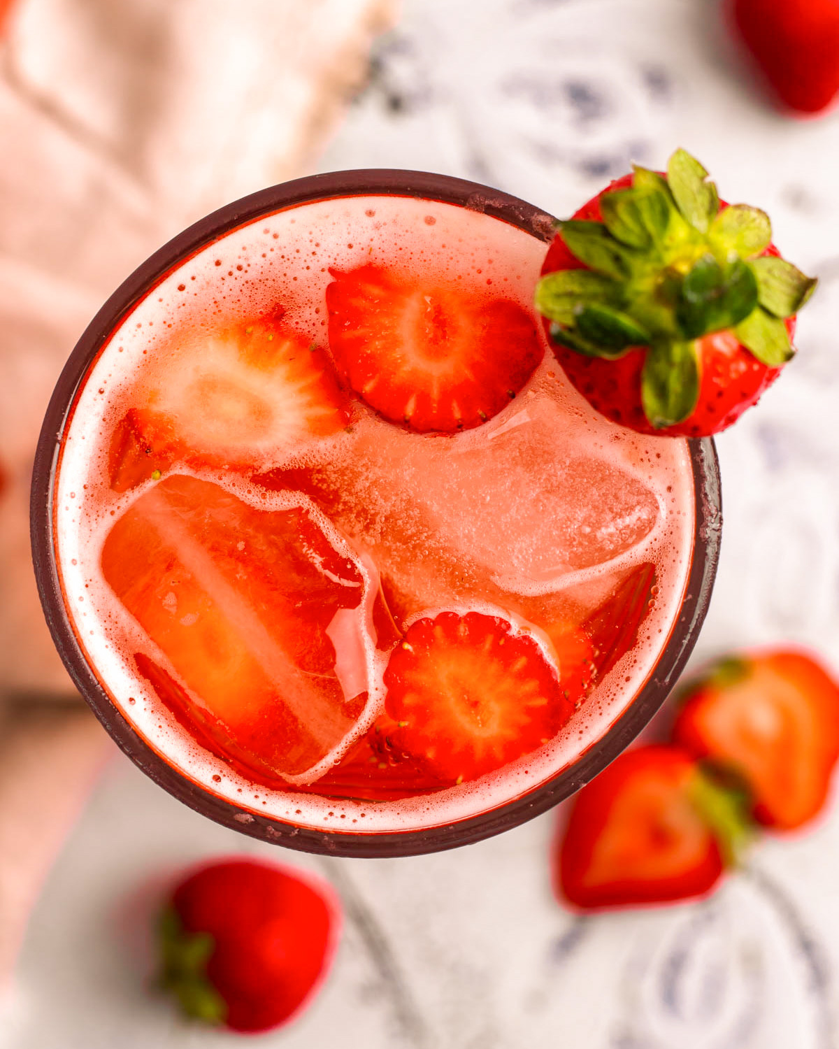 A closeup overhead shot of a glass of strawberry soda on the counter.