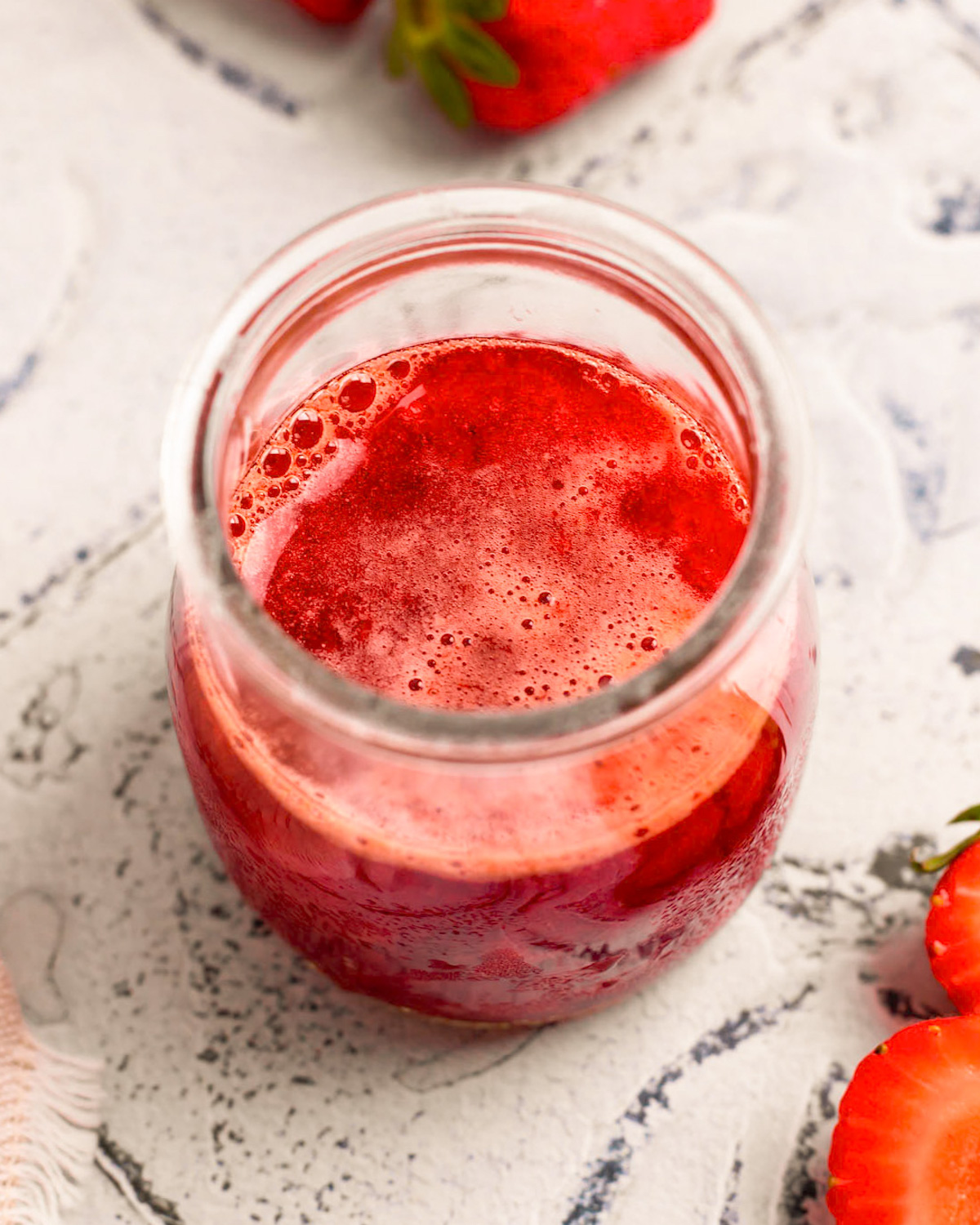 An up-close angled shot of a small cup of the simmered strawberry mixture.