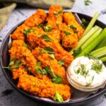 side view of vegan buffalo wings on a plate with celery and dairy-free ranch dip