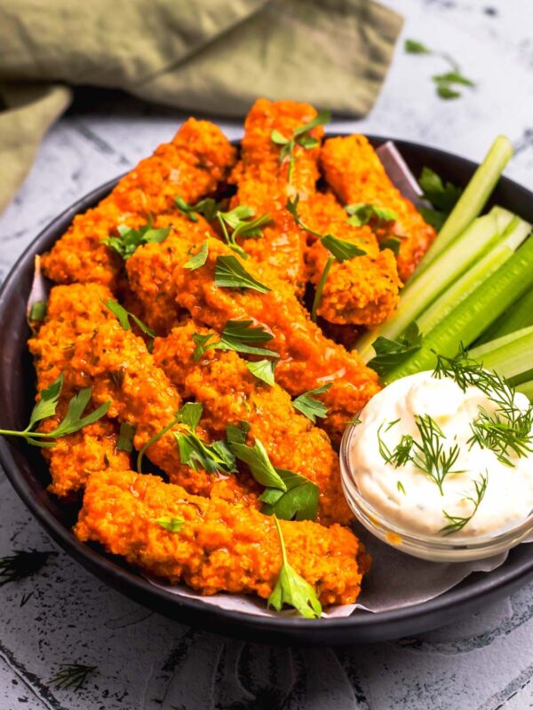 side view of vegan buffalo wings on a plate with celery and dairy-free ranch dip