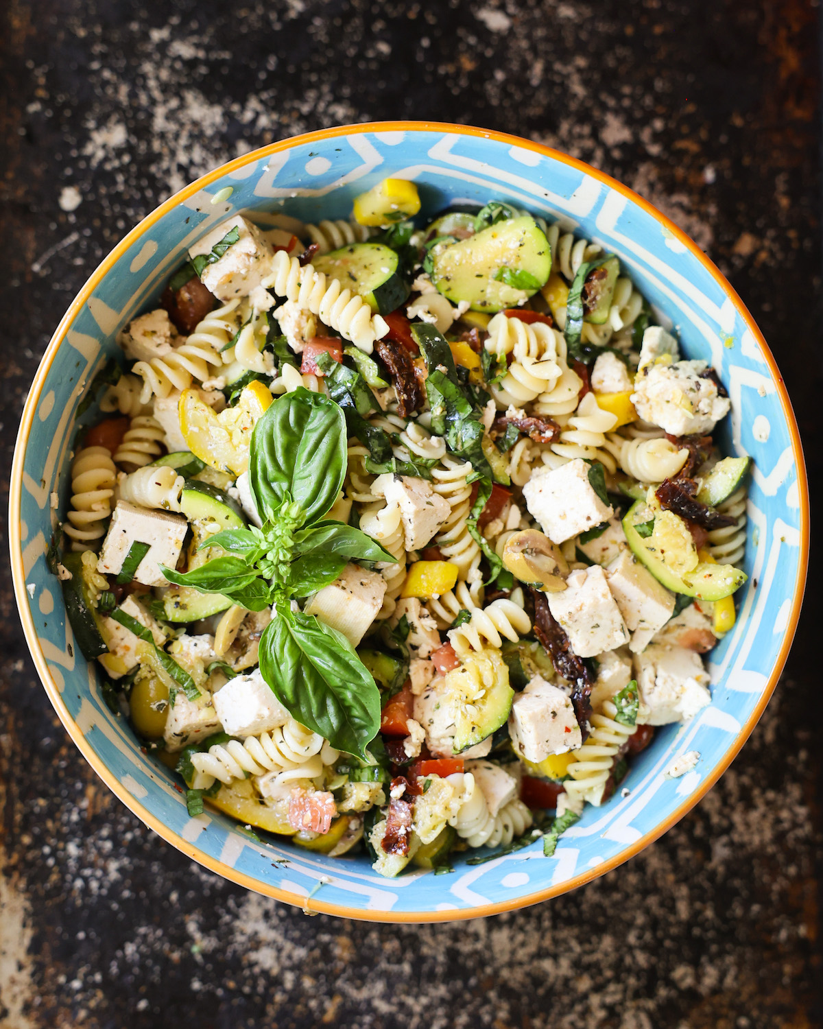 An overhead shot of a bowl of Mediterranean pasta salad with basil.