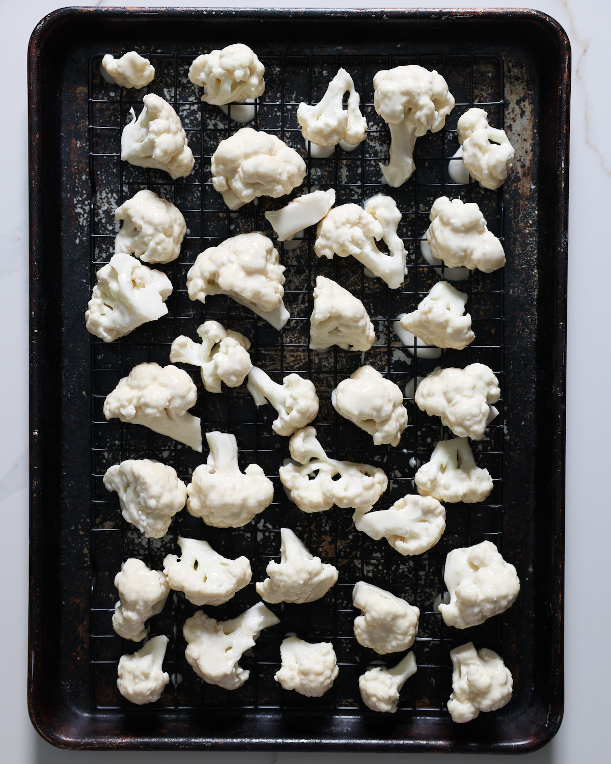 A baking pan with battered cauliflower on it.