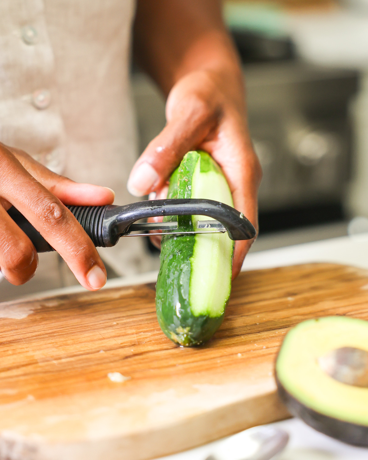 brown hands peeling a cucumber