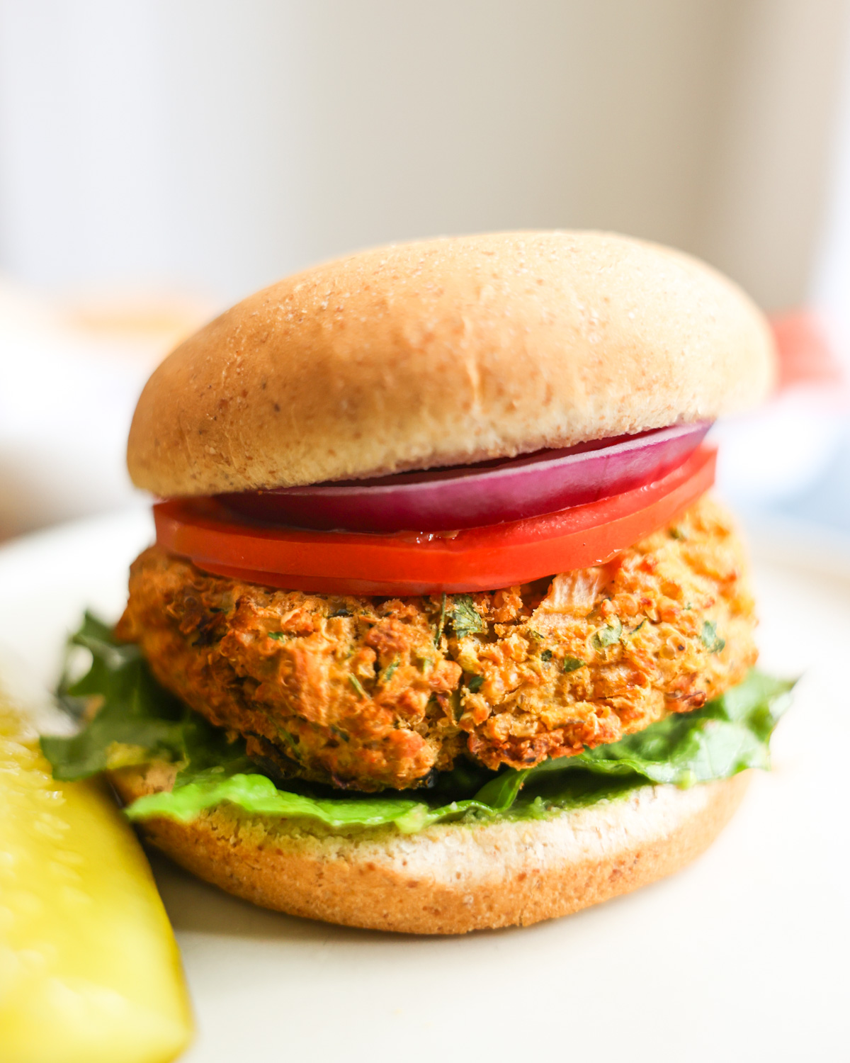 side view of quinoa zucchini burger with a pickle