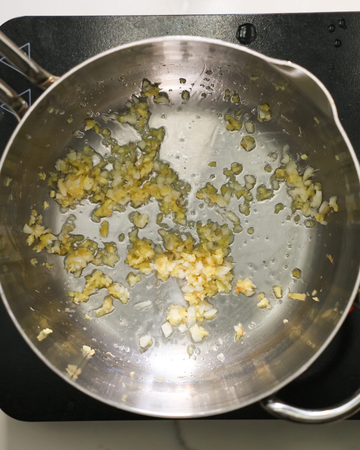 An overhead shot of minced garlic sauteeing in a pan.