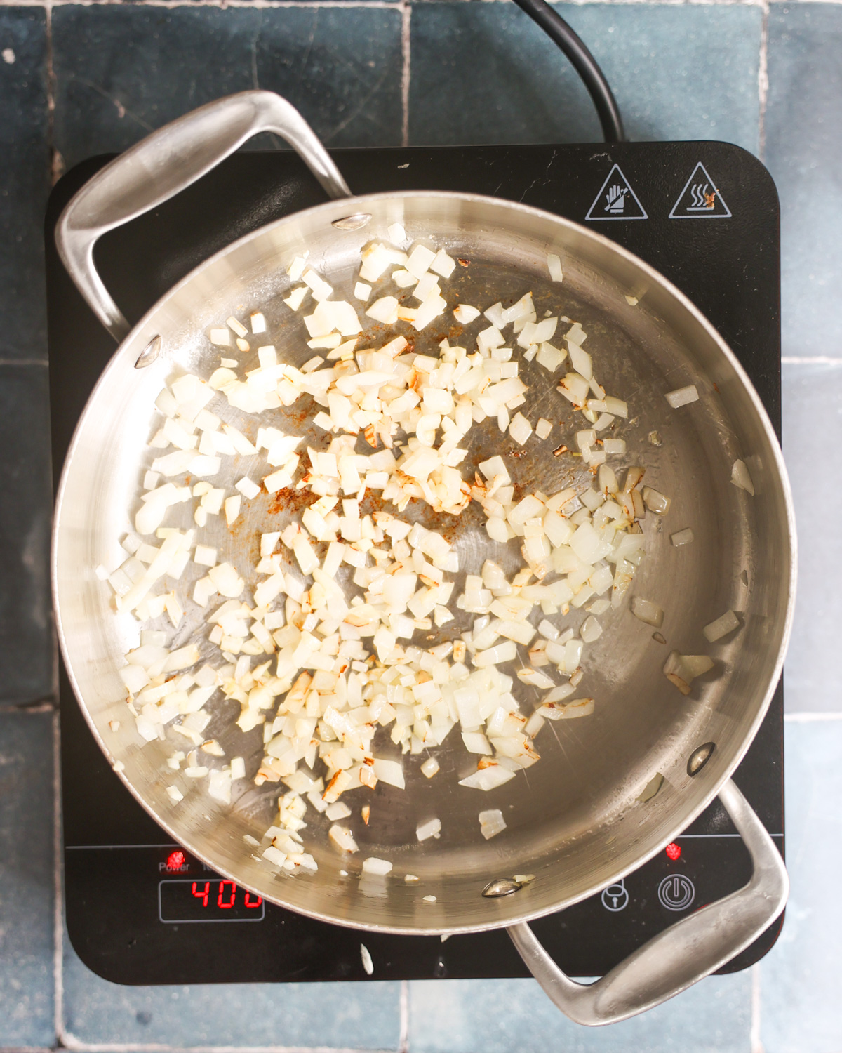 overhead of onions sautéing in pan for zucchini burgers