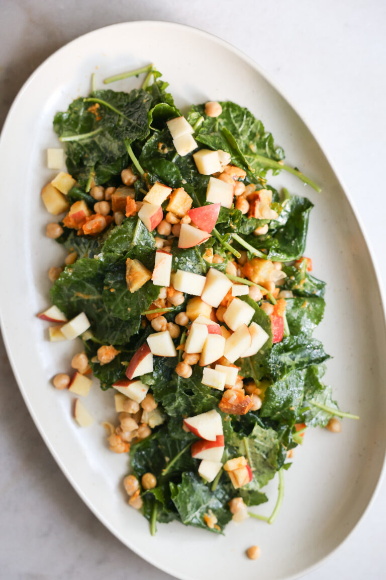 overhead of baby kale salad on white platter