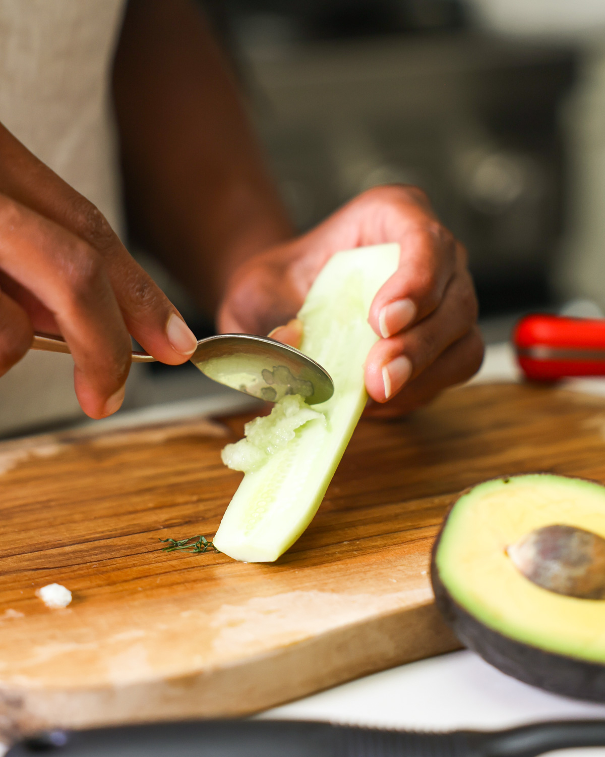 brown hands scooping seeds from a cucumber